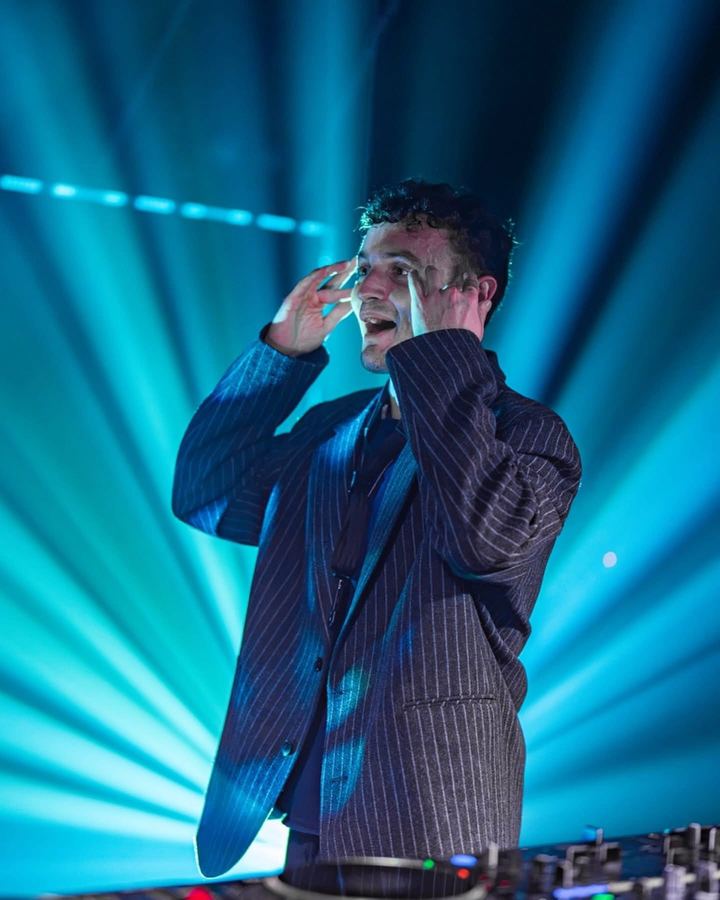 A Gridlock artist performing behind the decks under blue stage lasers.