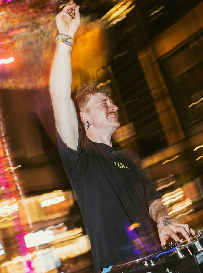A Gridlock artist mid-set with an arm raised, city lights blurred behind.